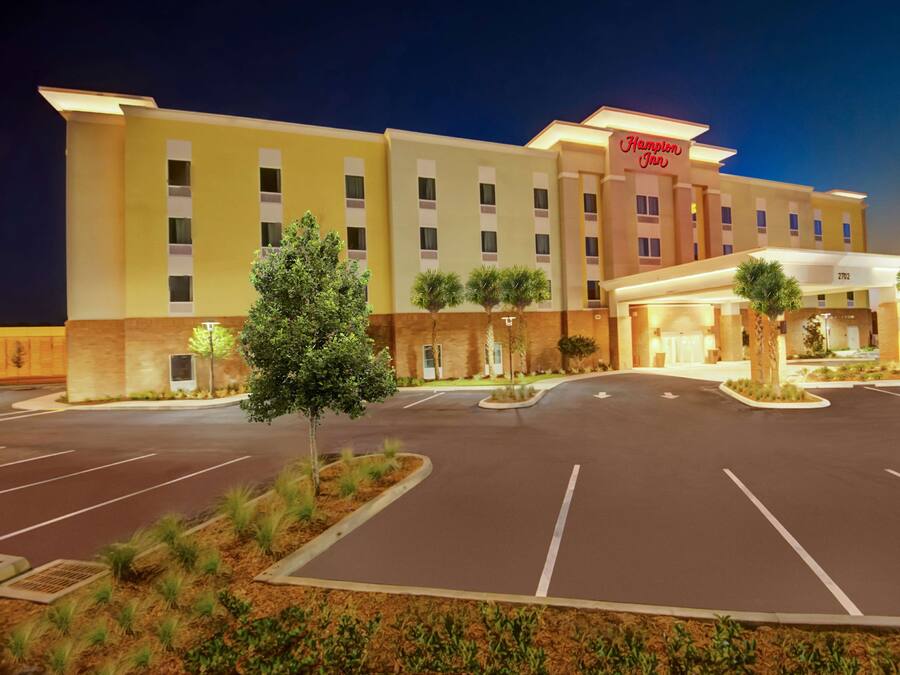 Un hotel Hampton Inn con estacionamiento y jardines.