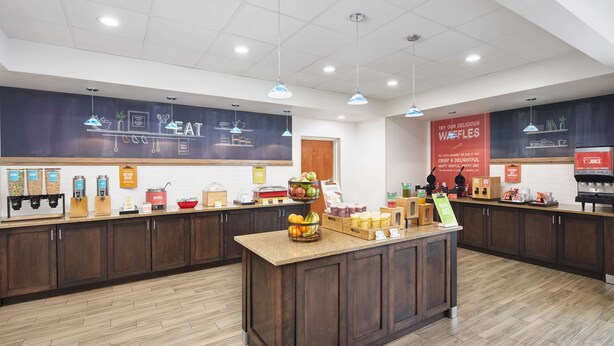 Een modern café met een centraal eiland, verschillende drank- en etensautomaatjes en een opvallende wafelpresentatie.