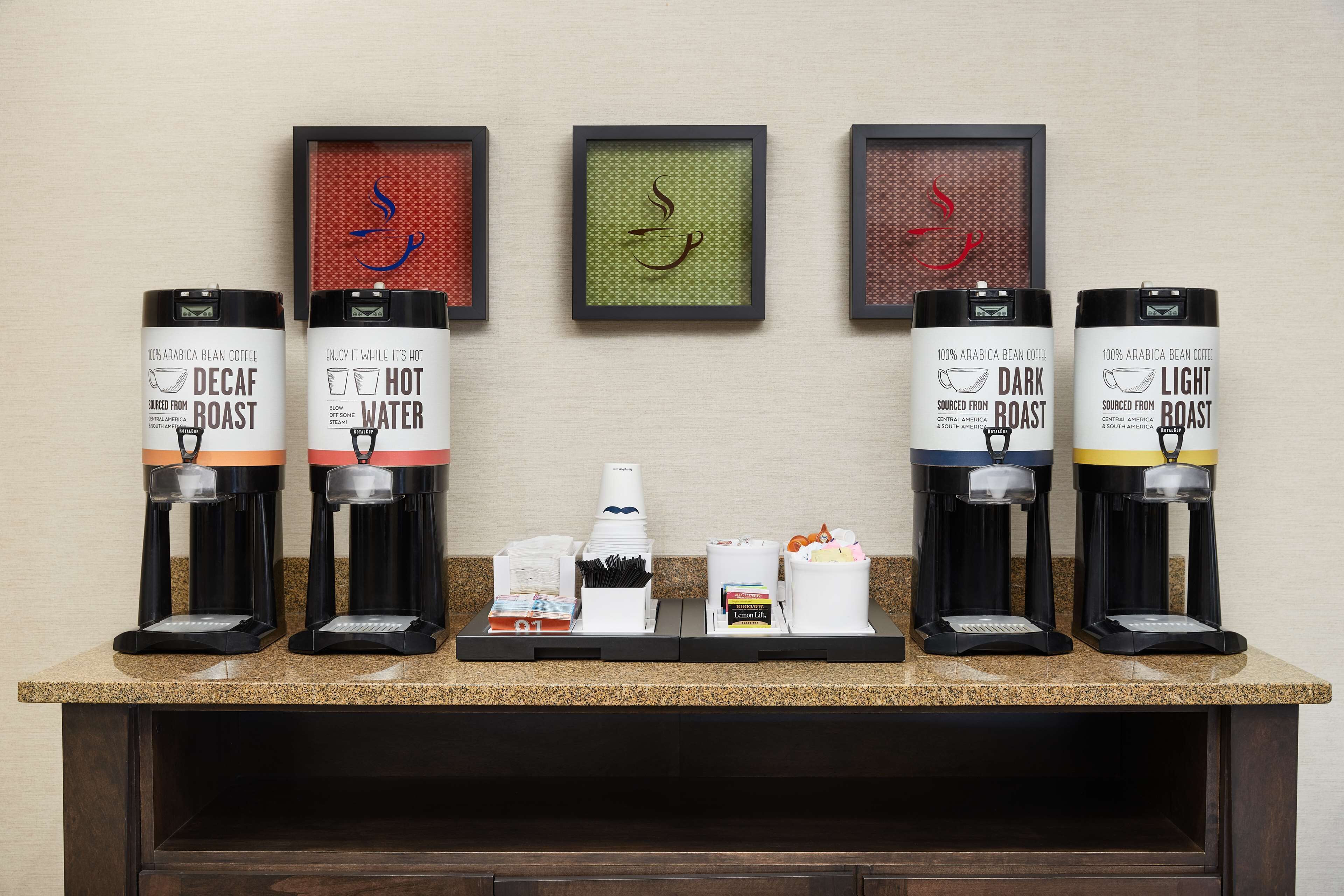 A coffee station with six dispensers labeled Decaf Roast, Hot Water, Dark Roast, and Light Roast.