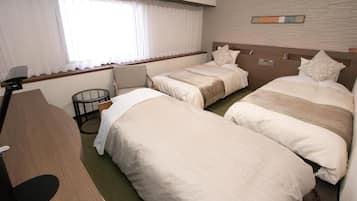 A hotel room with two single beds, a desk, and a window with curtains.