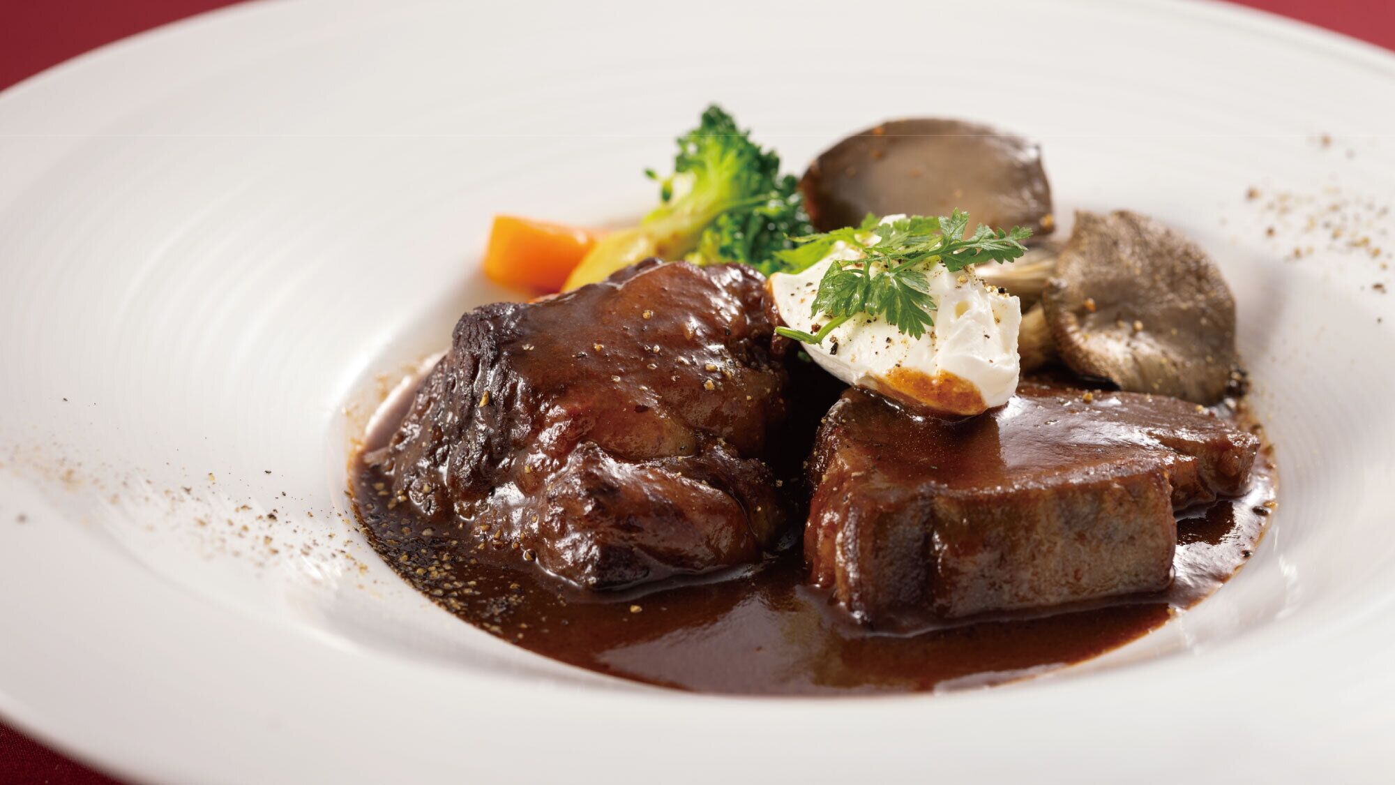 A plate with a beef dish, vegetables, and a garnish.