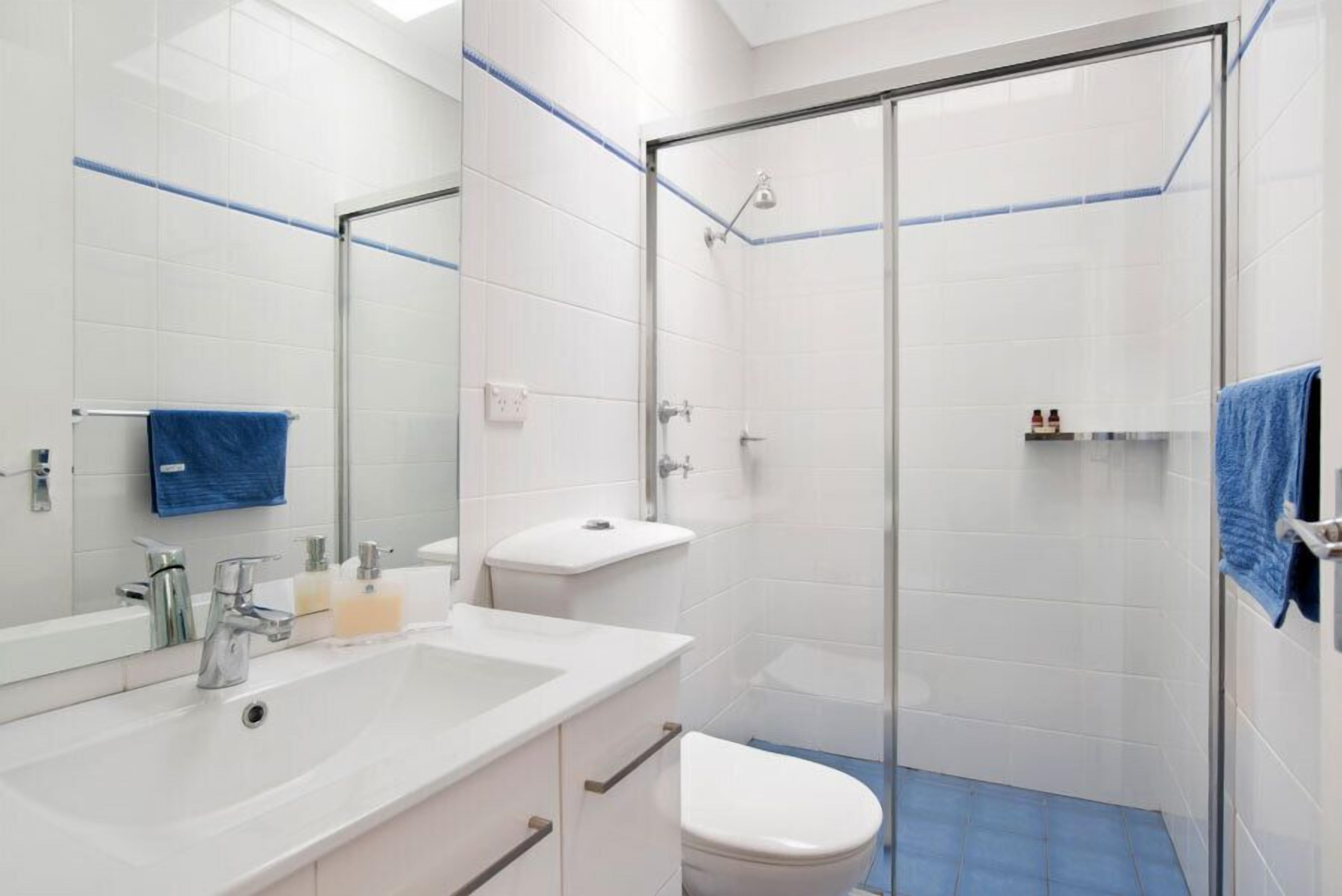 A modern bathroom with a glass shower enclosure, a white sink with a mirror, and a toilet.