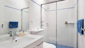 A modern bathroom with a glass shower enclosure, a white sink with a mirror, and a toilet.
