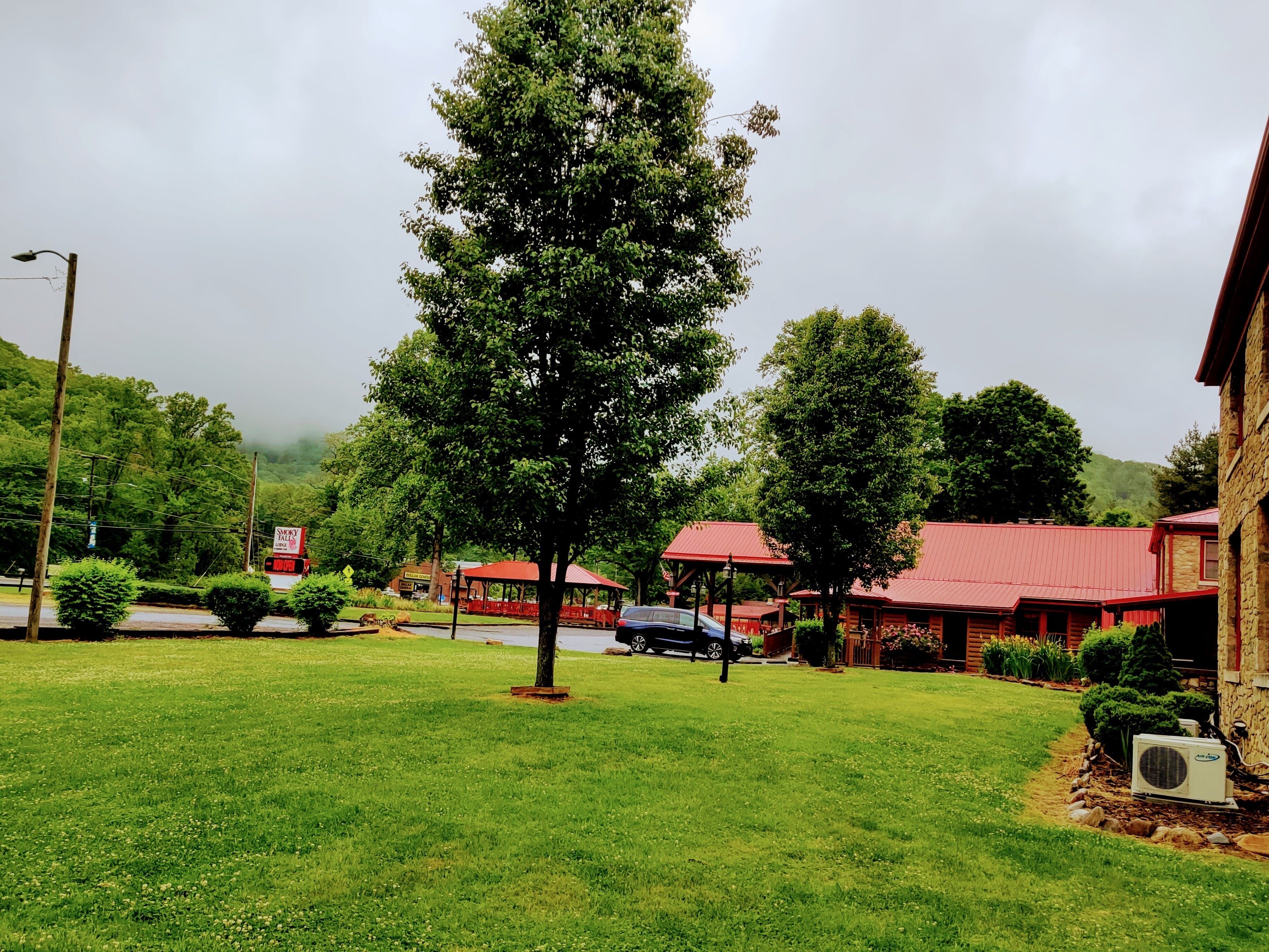 A grassy area with a large tree, a building with a red roof, and a sign for 'Smoky Falls'.