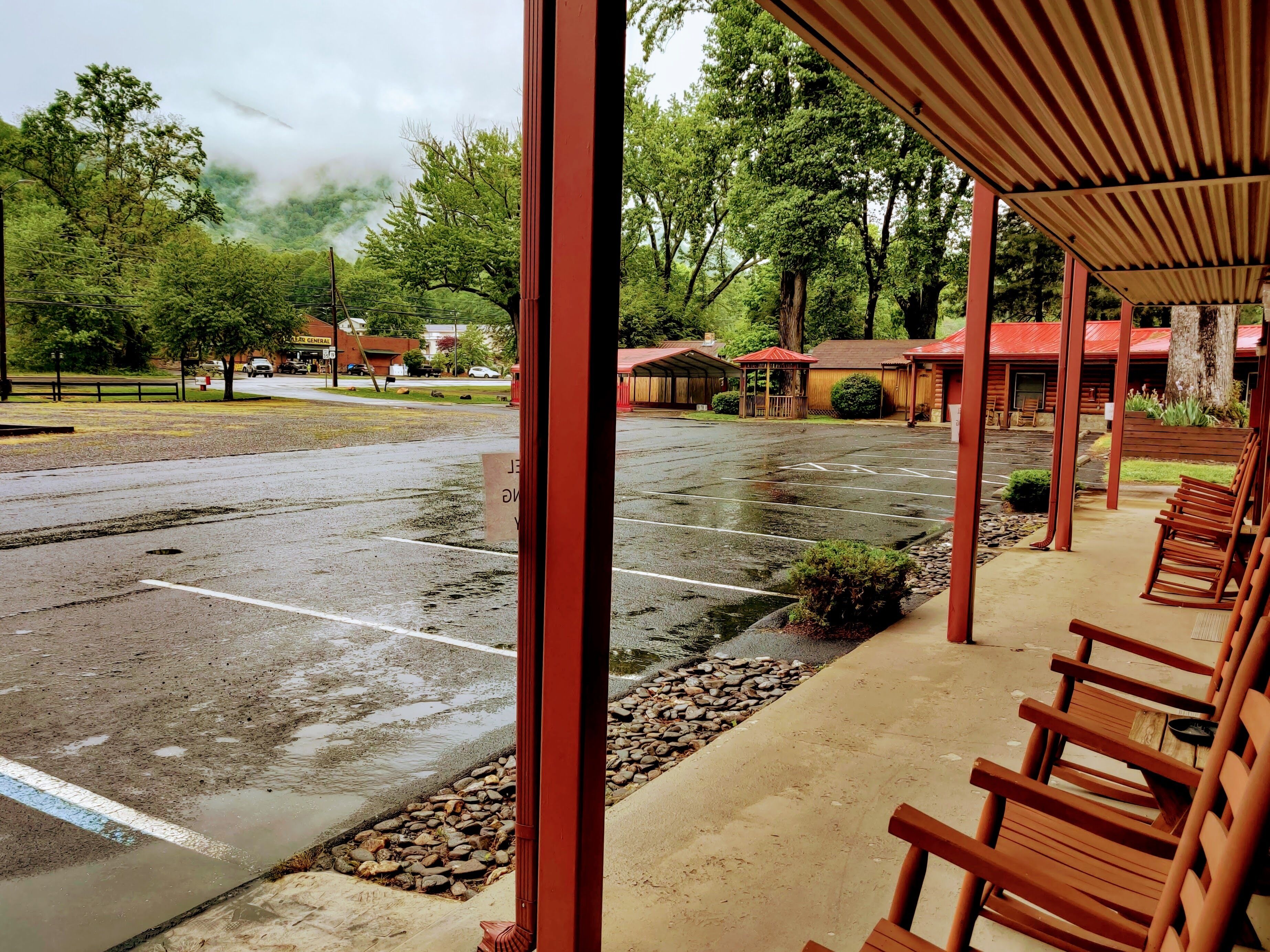 A view of a parking lot with a covered seating area and a building in the background.
