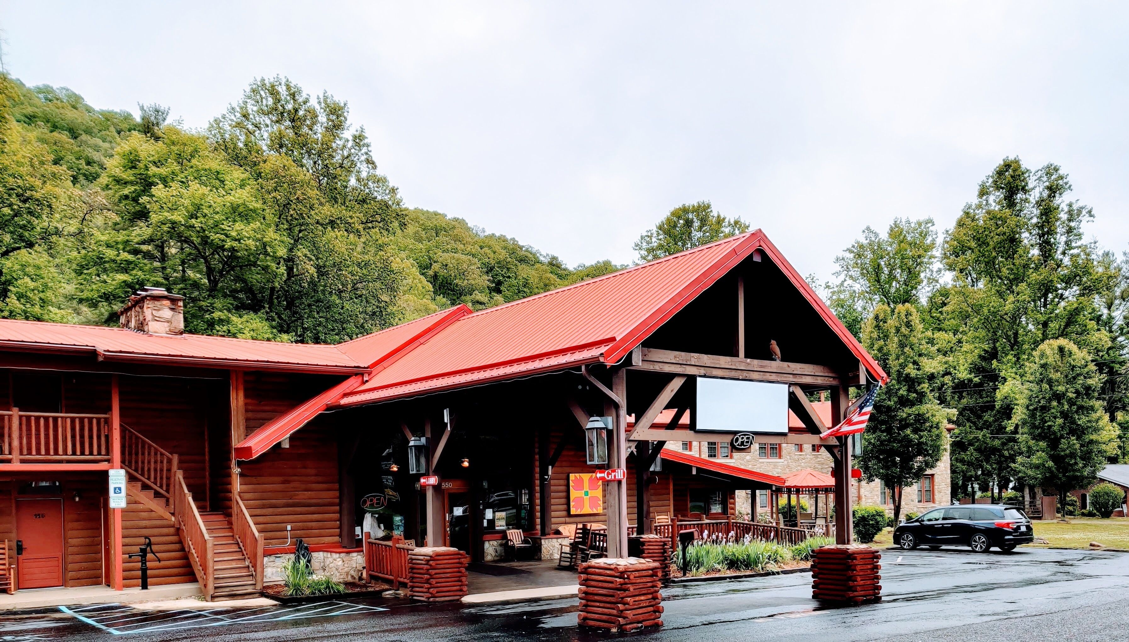 Ein rustikales Holzhaus mit rotem Dach, einer Veranda mit Sitzgelegenheiten und einem Schild, das ein Restaurant anzeigt.