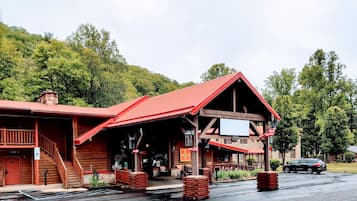 Ein rustikales Holzhaus mit rotem Dach, einer Veranda mit Sitzgelegenheiten und einem Schild, das ein Restaurant anzeigt.