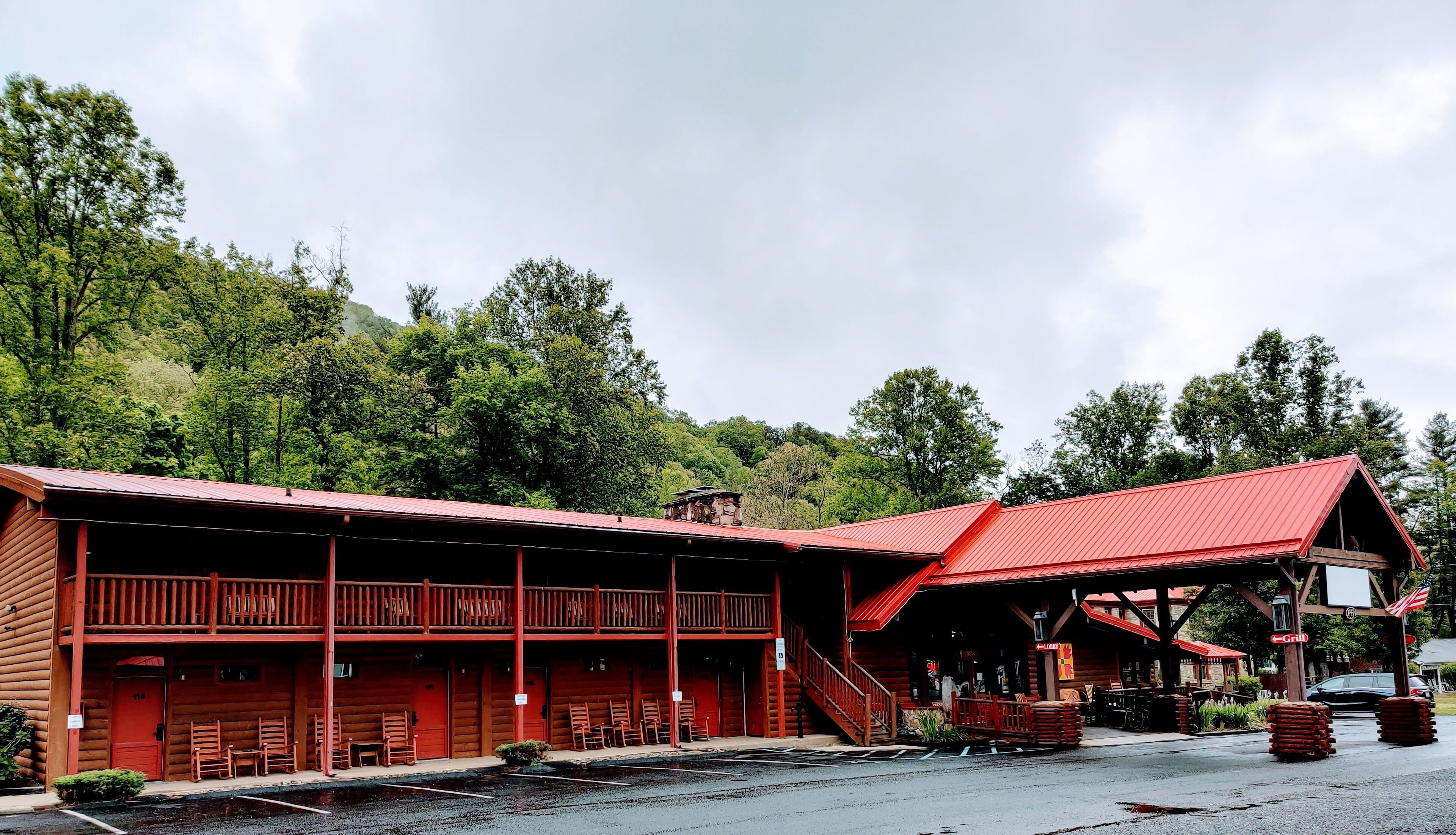 A log cabin-style building with a red roof, multiple rooms, and a porch area.