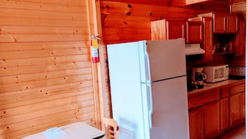 Une petite cuisine équipée avec un réfrigérateur blanc, des placards en bois, un four à micro-ondes et une table avec une chaise.