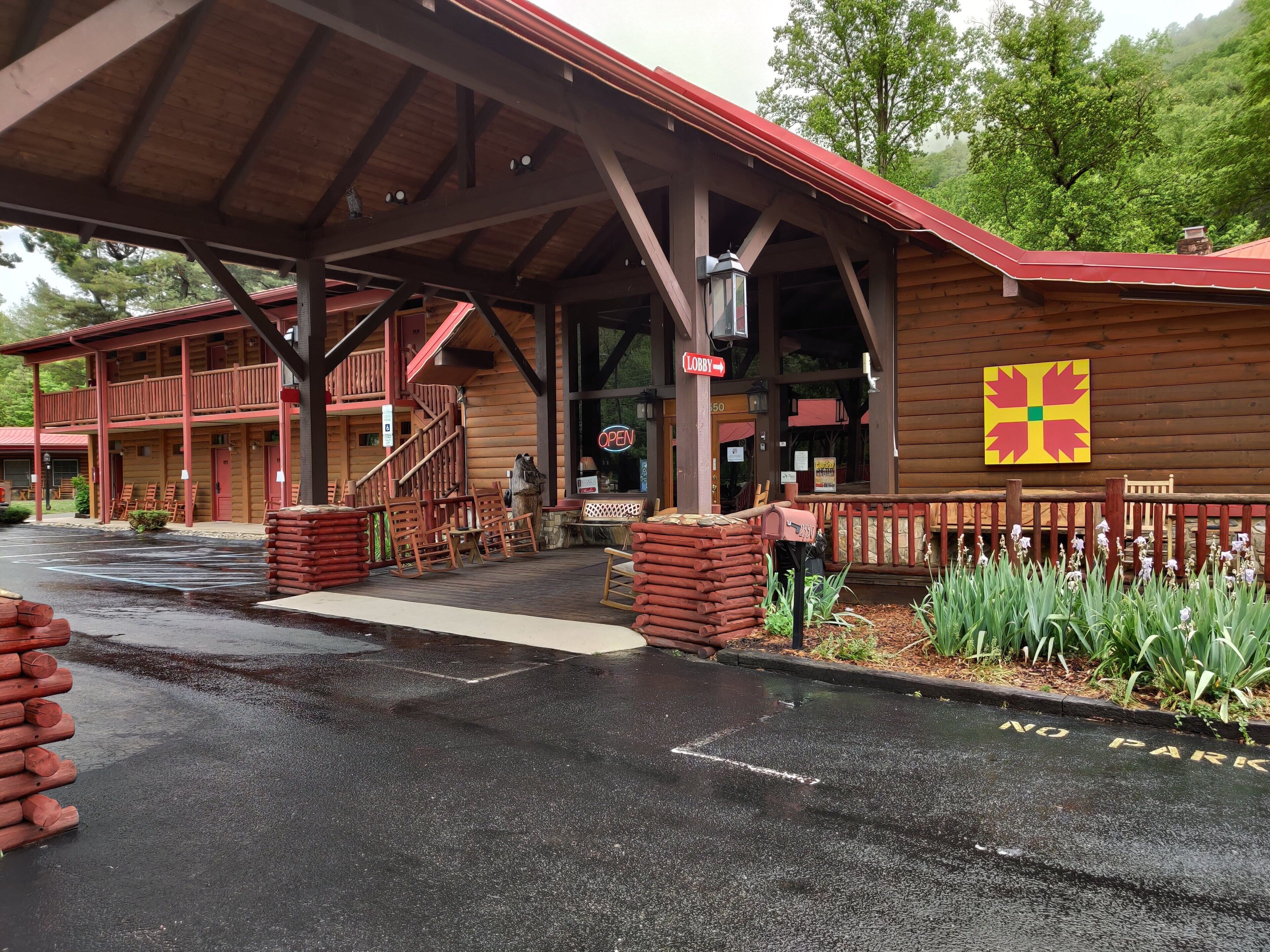 Un chalet rustique doté d’un porche, de sièges extérieurs et d’un panneau indiquant « Stationnement interdit ».