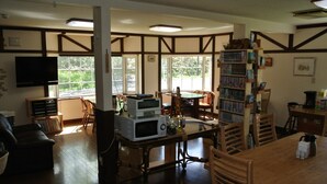 A cozy living room with a fireplace, a television, and a bookshelf. - Pension Megumiyuki (Biei)