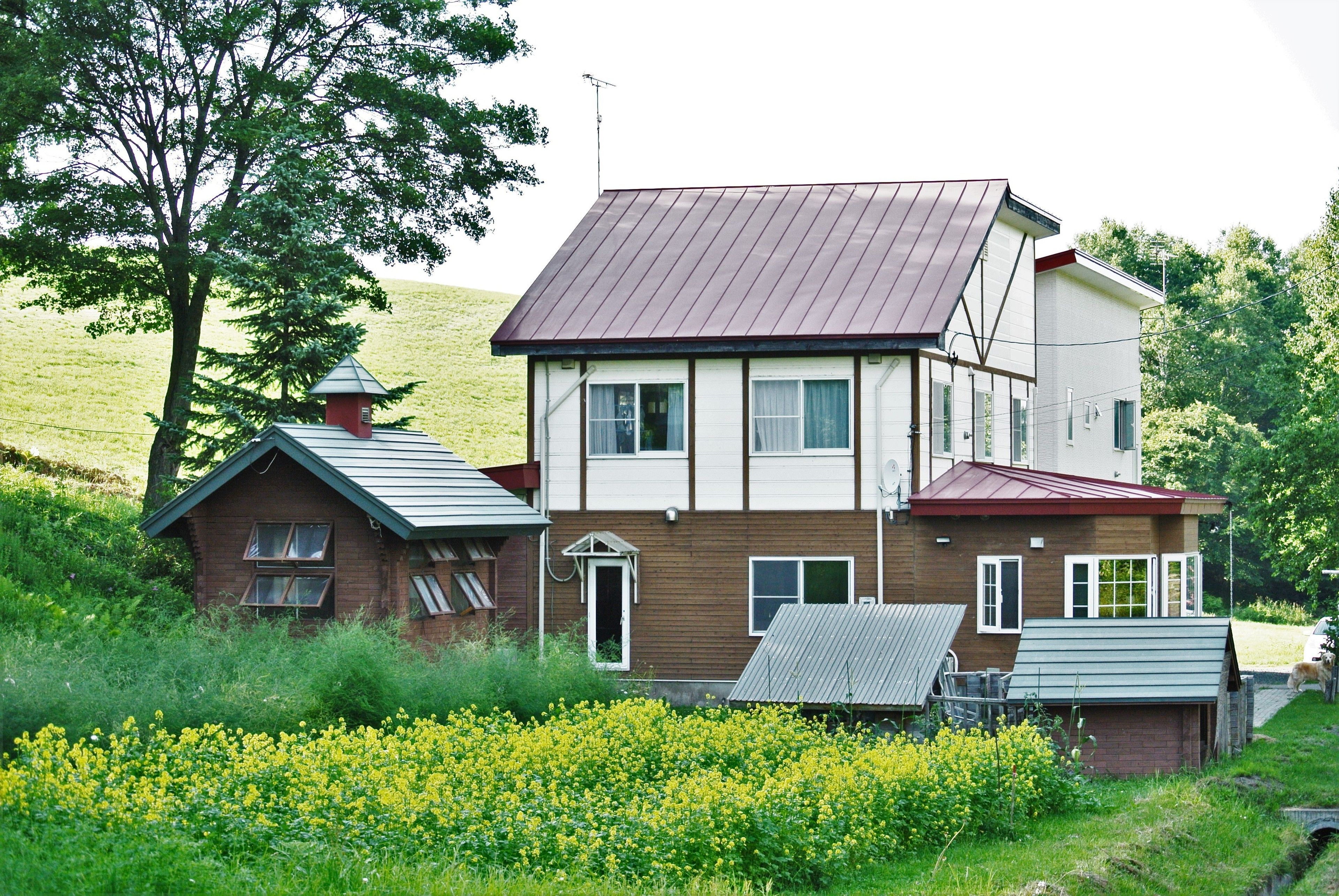A two-story house with a red roof, a wooden exterior, and a small attached garage.