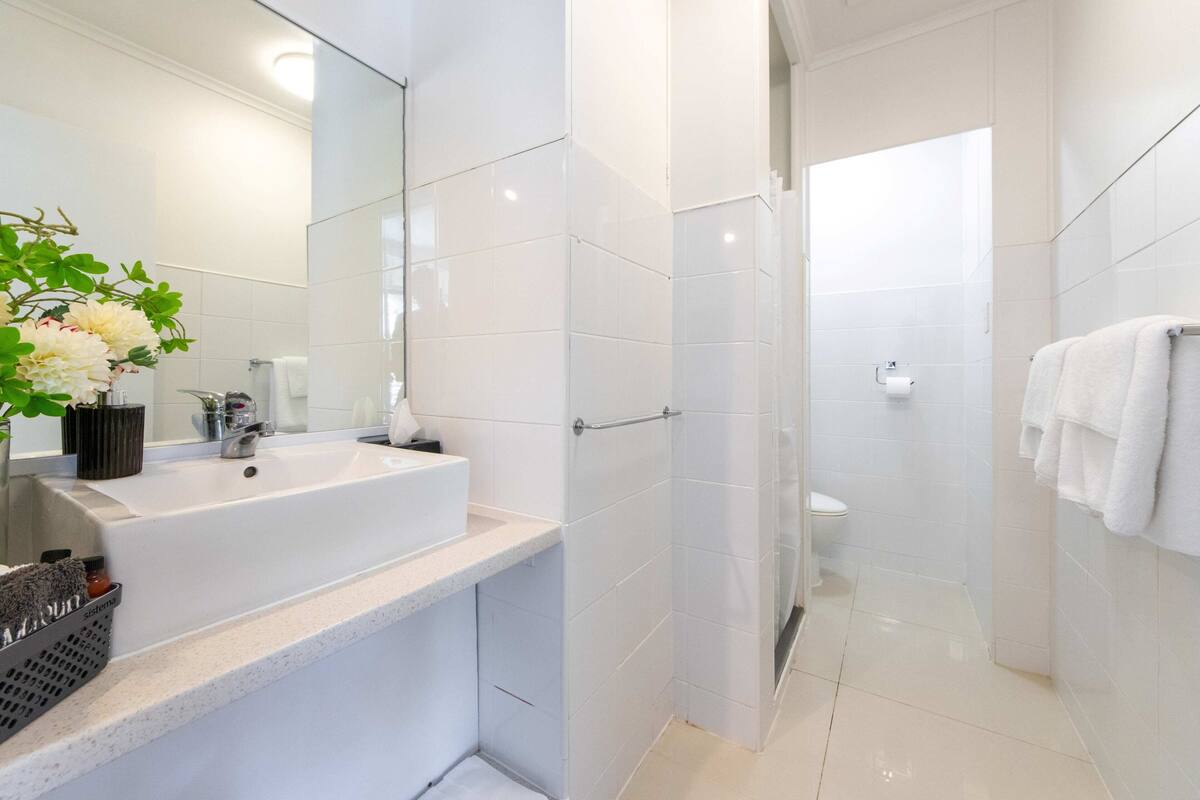 A modern bathroom with a white sink, mirror, and shower.