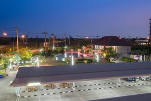 A parking area with a covered seating area, a swimming pool, and a building with a red roof. - The Cotai Luxury Design Hotel (Bang Sao Thong)