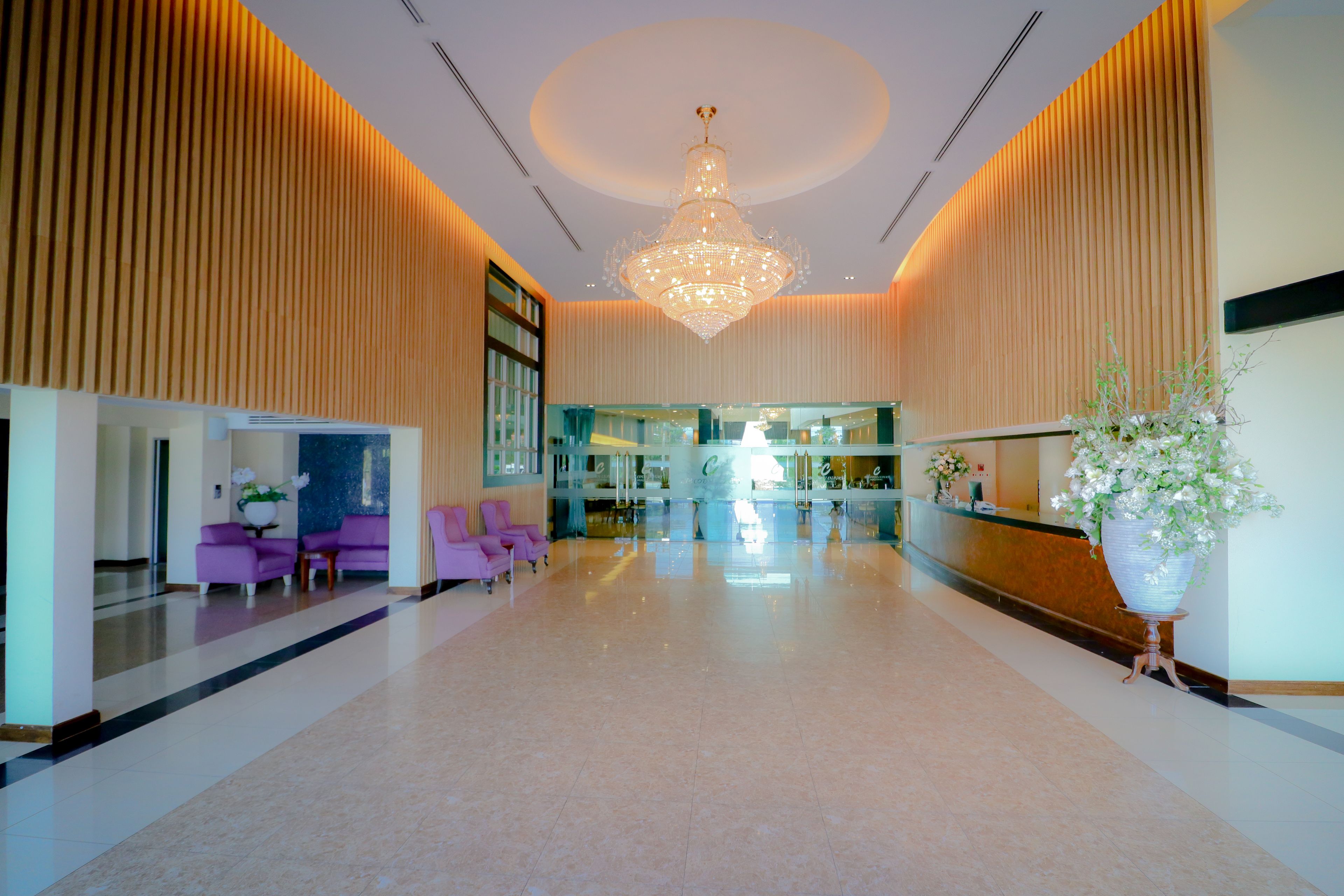 A spacious lobby with a chandelier, seating area, and reception desk.