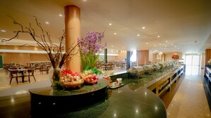 Un espace buffet avec un îlot central, des tables et des chaises, et une grande colonne.