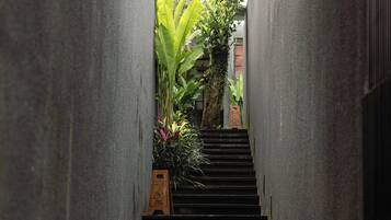 Una escalera estrecha bordeada por paredes de concreto, que lleva a una puerta con un letrero de precaución.