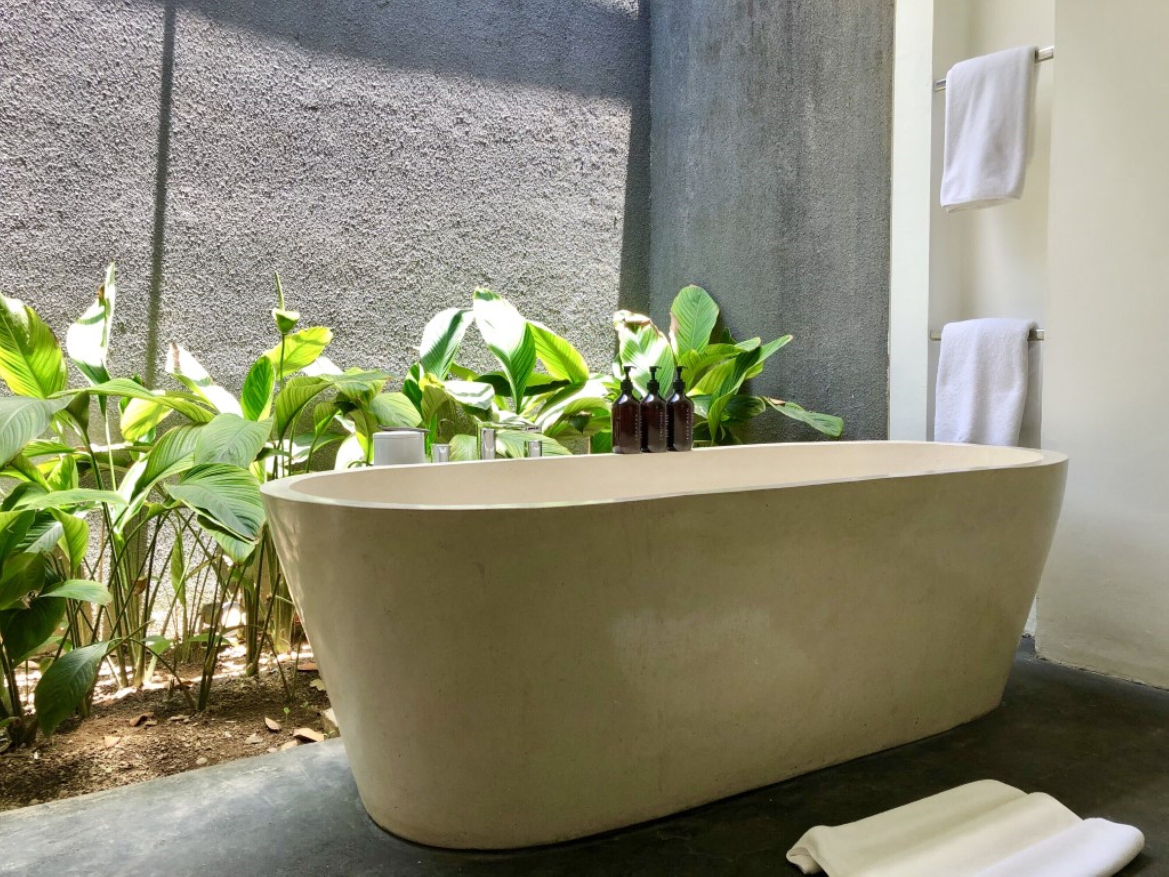 Una bañera independiente en un espacio de spa con plantas y toallas.