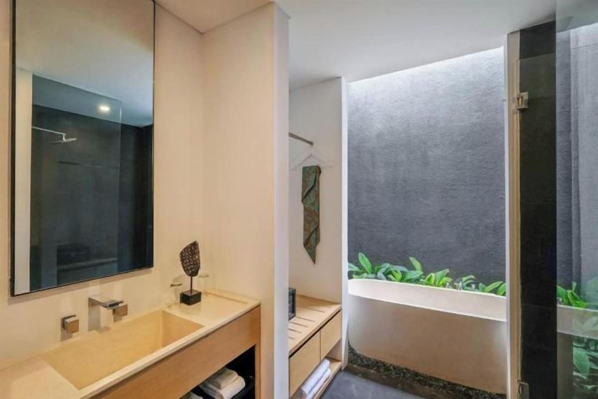 A modern bathroom with a large mirror, a beige sink, and a shower with a glass door.