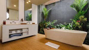 Un baño moderno con una bañera independiente, un mueble de tocador con espejo y un estante con toallas.