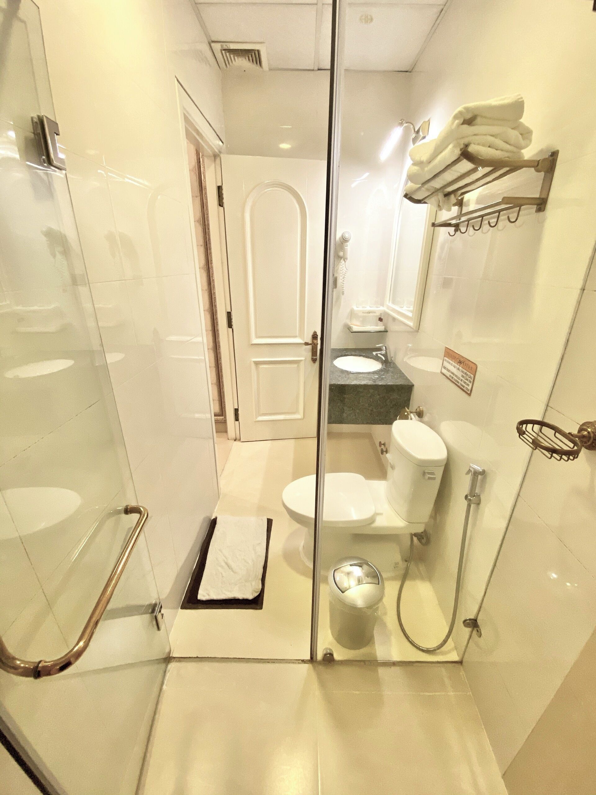 Een moderne badkamer met een glazen douchecabine, toilet, wastafel en douche.