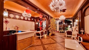 A hotel lobby with a reception desk, seating area, chandeliers, and a Christmas tree. - Tulip Hotel 3 (Xuan Huong - Da Lat)