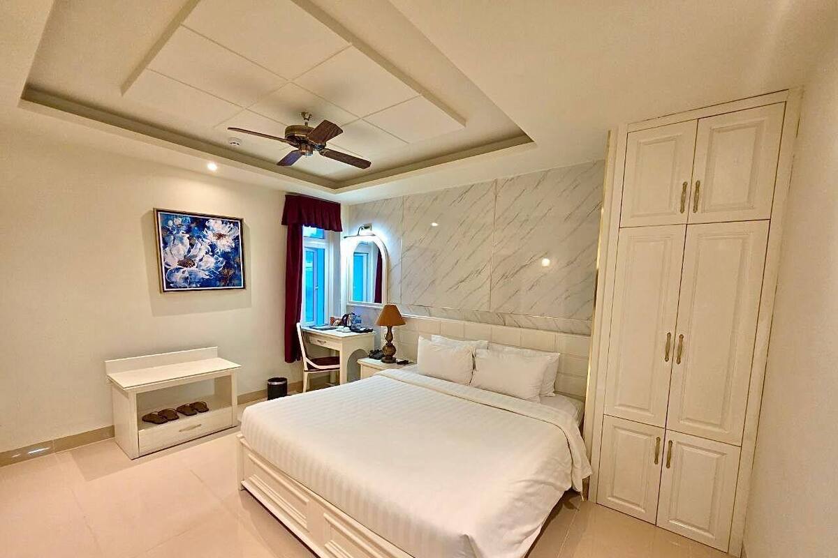 A bedroom with a bed, a desk, a wardrobe, and a ceiling fan.