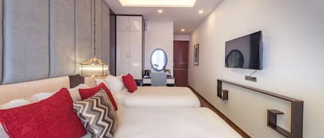 Habitación de hotel con una cama grande, ventilador de techo, televisor montado en la pared y escritorio con silla.