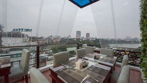 Un restaurant amb taules preparades per dinar, vista a la ciutat i sostre de vidre.