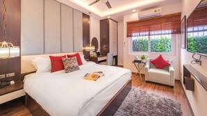 Habitació d'hotel moderna amb un llit gran, escriptori, cadira i televisió.