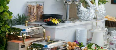 A buffet table with various food items, a decorative swan, and a vase of flowers.