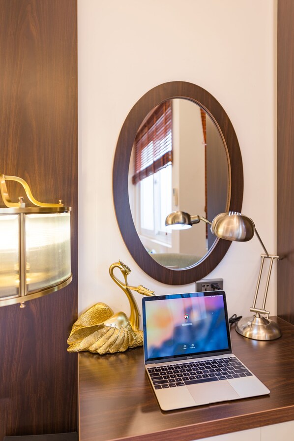 A laptop on a wooden desk with a round mirror, a lamp, and decorative shells. - Splendid Hotel & Spa (Hanoi)