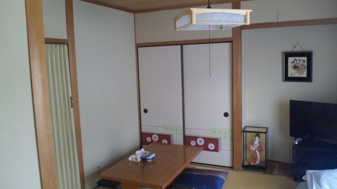 A traditional Japanese room with sliding doors, a wooden table, a framed picture, and a television.