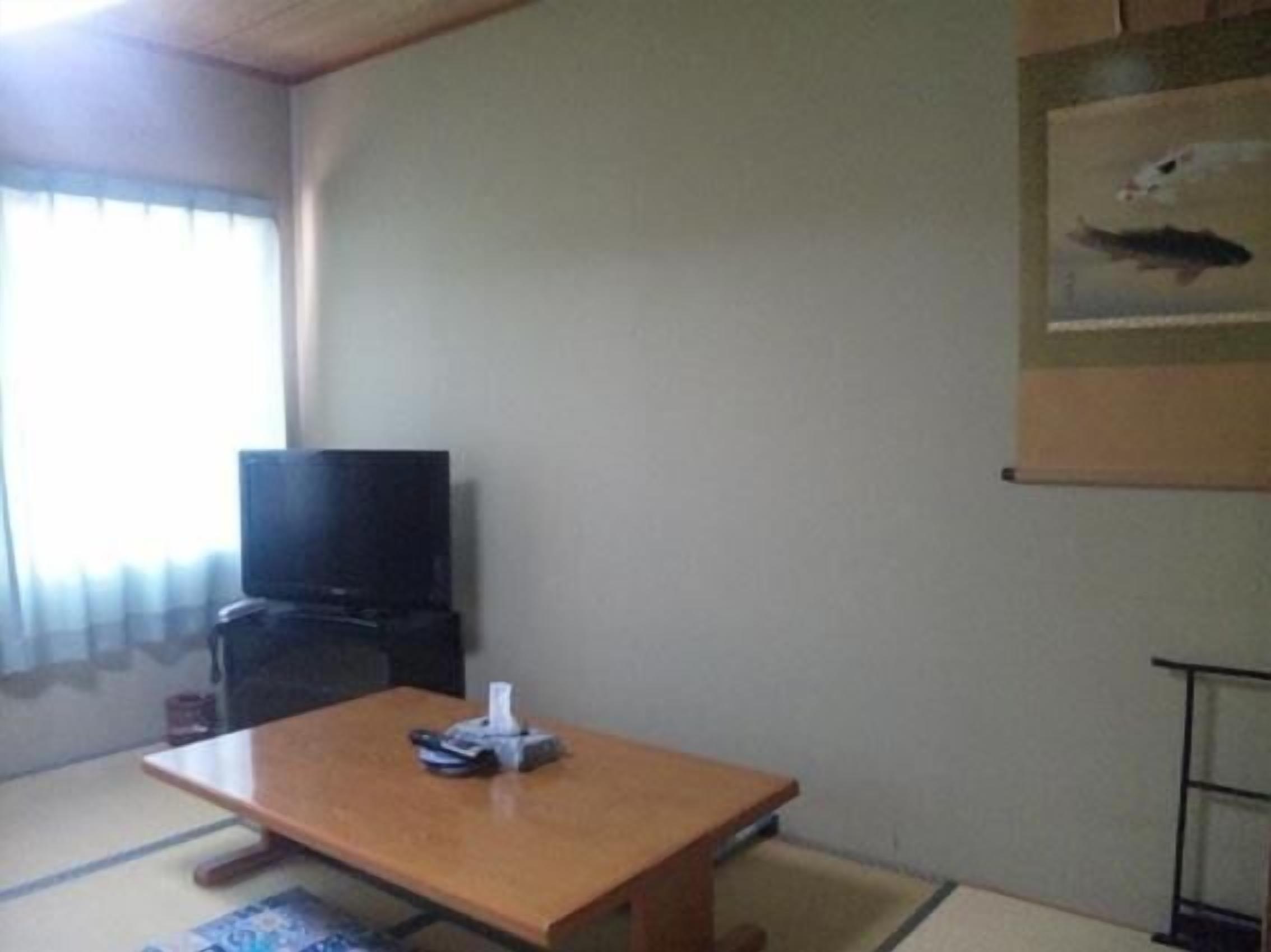 A room with a tatami mat floor, a wooden table, a television, and a painting on the wall.