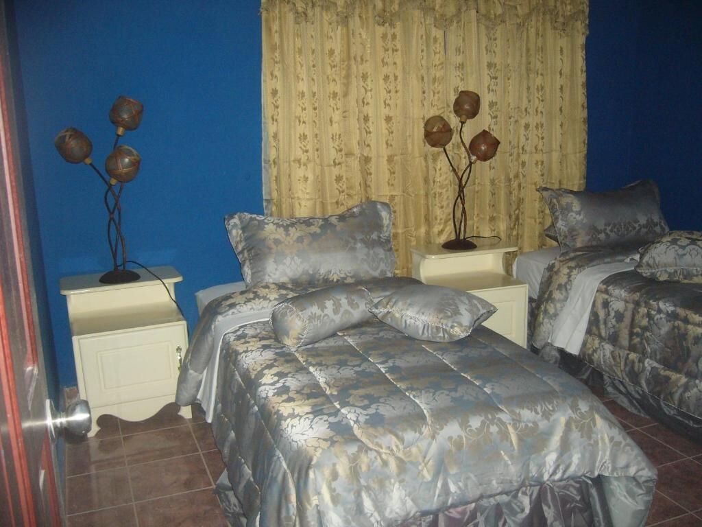 A bedroom with two beds, a nightstand, and a decorative vase on the nightstand.