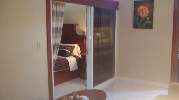 A bedroom with a bed, a sliding glass door, and a painting on the wall.