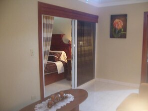 A bedroom with a bed, a sliding glass door, and a painting on the wall.