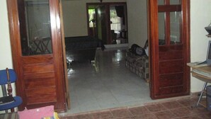 An open doorway leading to a living room with a sofa, a chair, and a ceiling fan.