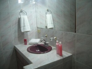 A bathroom with a marble sink, a mirror, and two towels hanging on towel rings.