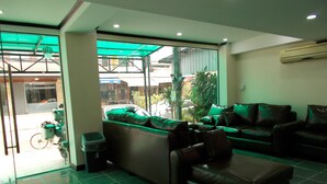 A modern lobby with a green-lit seating area, a bicycle outside, and a view of the street. - Memory Hotel (Vientiane)