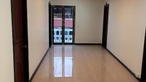 A spacious hallway with a polished floor, dark trim, and a large glass door leading outside. - Memory Hotel (Vientiane)