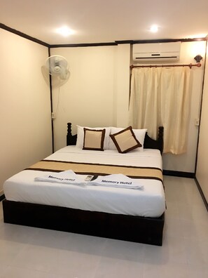 A hotel room with a bed, a fan, an air conditioning unit, and a curtain. - Memory Hotel (Vientiane)