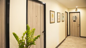 Un pasillo con puertas de madera, una planta en maceta y cuadros en las paredes.