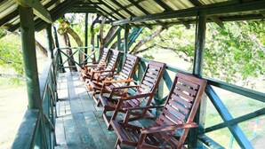 Un espace extérieur abrité, avec des chaises en bois et une rambarde en métal.