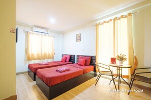 A twin room with two beds, a small table with a chair, and a window with curtains. - Nittaya Residence (Bangkok)