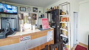 A reception desk with a television, a clock, and a sign welcoming guests. - Nittaya Residence (Bangkok)