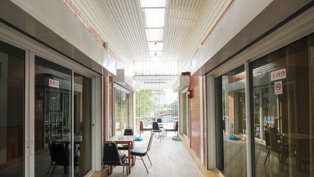 A corridor with glass doors, a wooden floor, and a table with chairs. - Nittaya Residence (Bangkok)