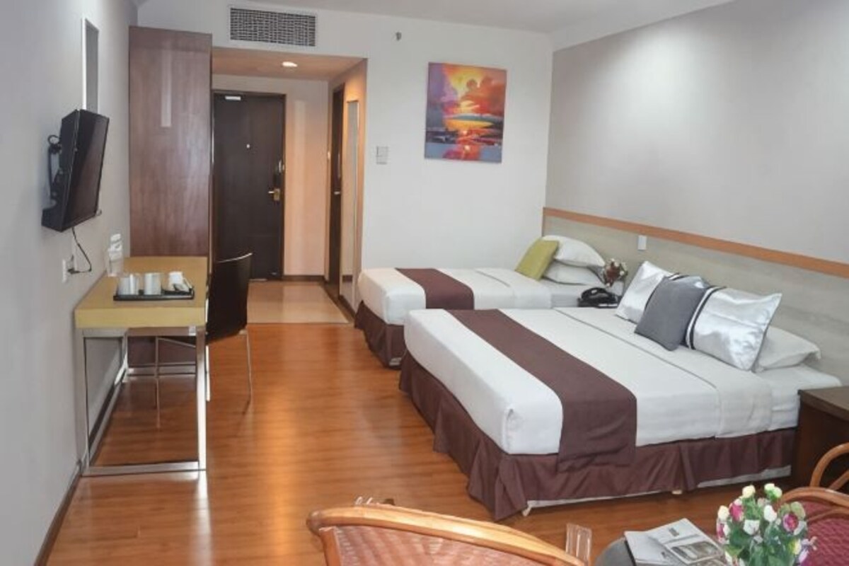 Une chambre d’hôtel avec deux lits, un bureau, une chaise et un téléviseur.