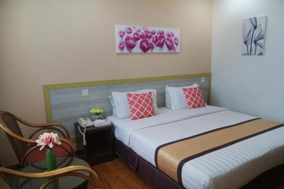 Une chambre d’hôtel avec un lit, une table de chevet, une chaise et des œuvres d’art accrochées aux murs.
