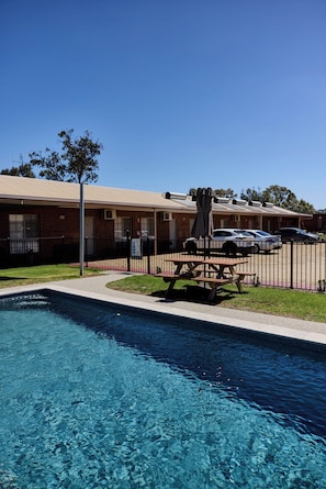 A swimming pool with a picnic table and a fence.